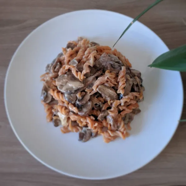 Fusilli de lentejas rojas con cebolla caramelizada, rulo de cabra y setas a la crema