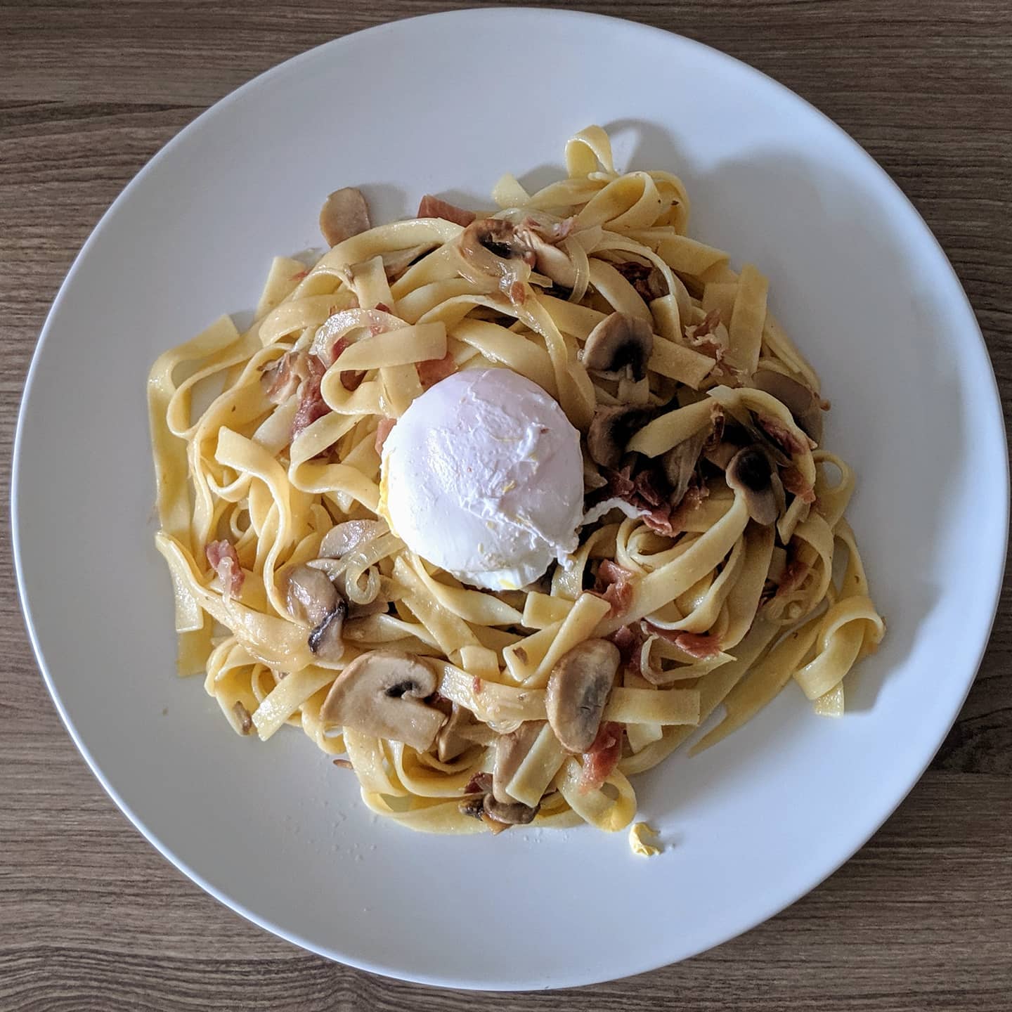 Tallarines salteados con champiñones y jamón con huevo escalfado