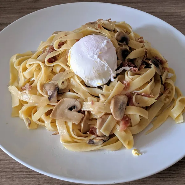 Tallarines salteados con champiñones y jamón con huevo escalfado
